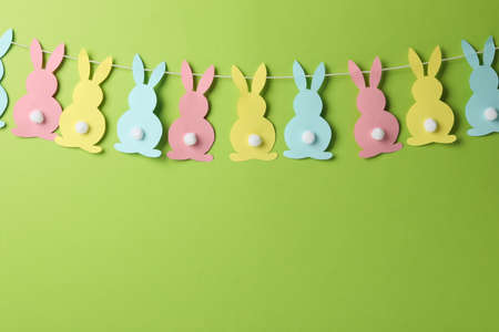 Twine with colorful bunnies on green background, space for textの写真素材