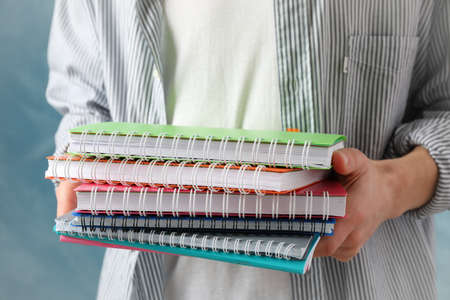 Person hold copybooks against blue background, close upの写真素材