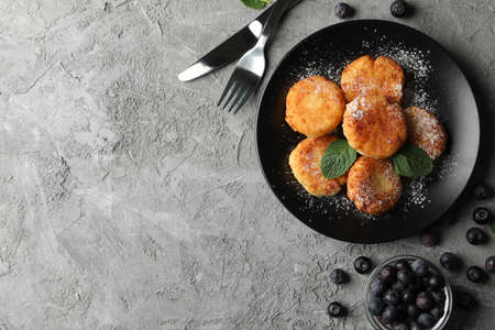 Breakfast of cheese pancakes on grey background, top view