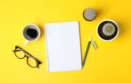 Notebook, glasses, coffee, pen and cacti on yellow background, top view