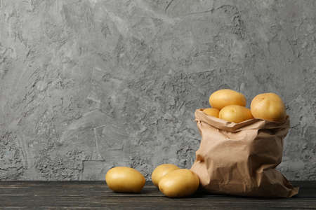 Paper bag with young potato on wooden background, space for textの写真素材