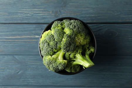 Bowl with broccoli on wooden background, top view. Healthy food
