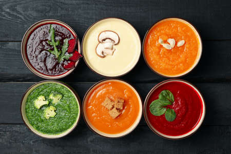 Flat lay with vegetable soups on wooden background, top view
