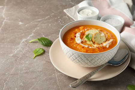 Pumpkin cream soup on grey background, space for text