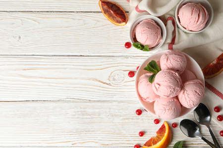 Bowls with ice cream balls on white wooden table, top view
