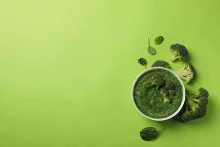 Broccoli cream soup on green background, top view