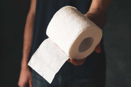 Man in t-shirt holds toilet paper, close upの写真素材
