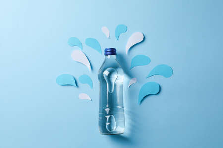 Bottle with water on decorative blue background, top view