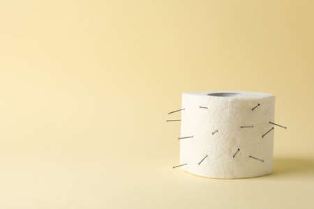 Toilet paper with nails on beige background. Hemorrhoidsの写真素材