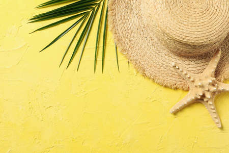 Straw hat, palm branch and starfish on yellow background, top viewの写真素材