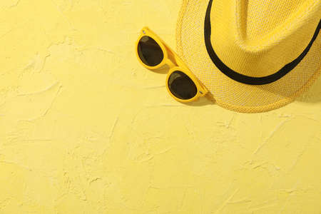 Hat and sunglasses on yellow background, top viewの写真素材