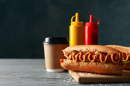 Tasty hot dogs, coffee and sauces on wooden backgroundの写真素材