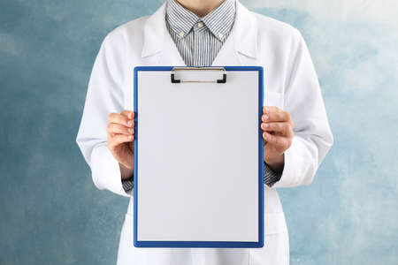 Doctor holds empty tablet on blue background, space for textの写真素材
