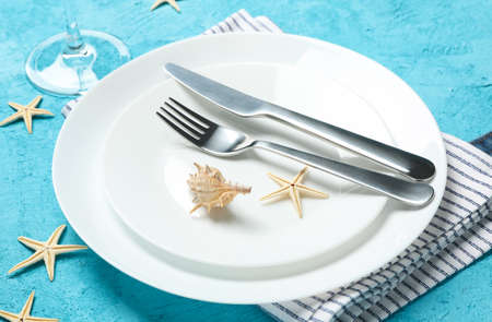 Table setting with seashells and starfishes on turquoise background, close upの写真素材