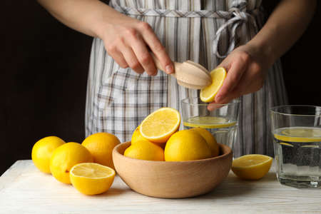Woman squeezes juice. Composition with lemons. Ripe fruitの写真素材