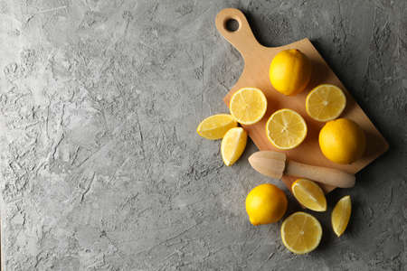 Board, lemons and juicer on gray background. Ripe fruitの写真素材