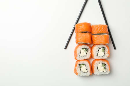 Chopsticks and sushi rolls on white background, space for textの写真素材