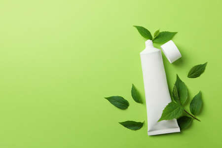 Toothpaste tube and mint leaves on green background, space for textの写真素材