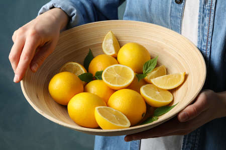 Woman holds bowl with lemons. Ripe fruitの写真素材