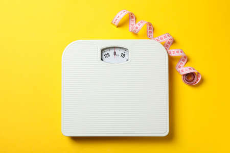 Scales and measuring tape on yellow background. Weight loss conceptの写真素材