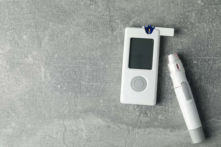 Blood glucose meter on gray background, space for text