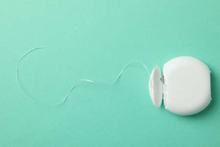 Tooth floss on mint background, space for text