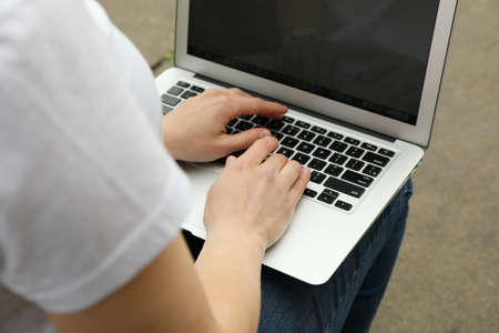Woman with laptop works in park. Outdoor workの写真素材