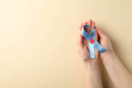 Female hands hold diabetes awareness ribbon on beige backgroundの写真素材