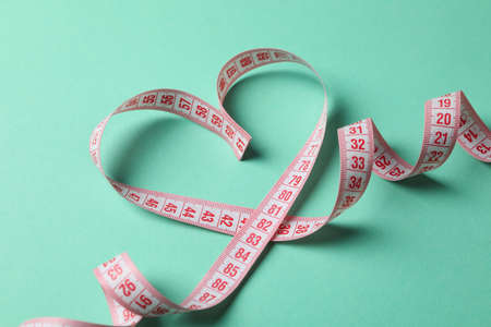 Measuring tape in the form of heart on mint backgroundの写真素材