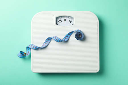 Scales and measuring tape on mint background. Weight loss conceptの写真素材