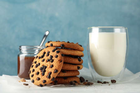 Composition with chip cookies, milk and caramel on white wooden table