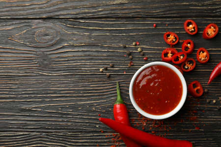 Chilli pepper and bowl of sauce on wooden  background, top viewの写真素材