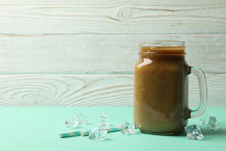 Jar of ice coffee, ice cubes and straws on mint tableの写真素材