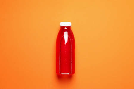Blank bottle with juice on orange background, space for textの写真素材