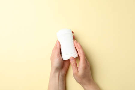 Female hands hold body deodorant on beige background, top viewの写真素材
