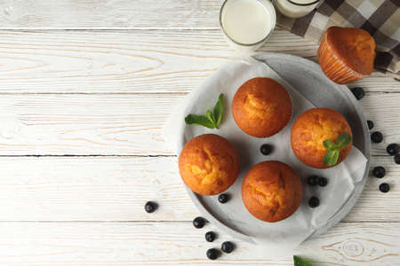 Composition with muffins and milk on white wooden background
