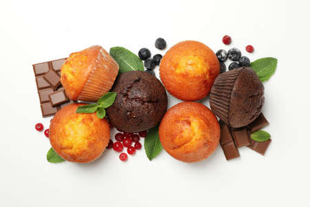 Muffins, berries and chocolate on white background, top view