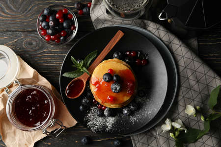 Plate of tasty pancakes with berry and powder on wooden table. Composition of sweet breakfastの写真素材