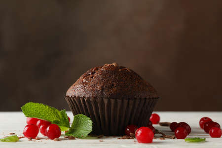 Chocolate muffin and berries against brown background
