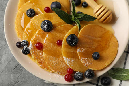 Plate of tasty pancakes with berry on gray table. Composition of sweet breakfastの写真素材