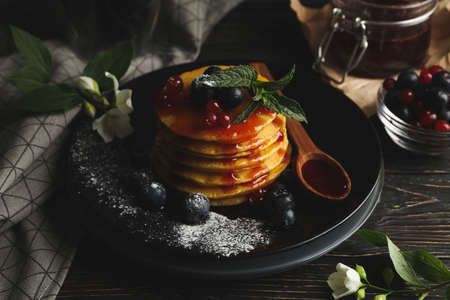 Plate of tasty pancakes with berry and powder on wooden table. Composition of sweet breakfastの写真素材