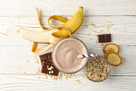 Glass of banana - chocolate milkshake on white wooden tableの写真素材