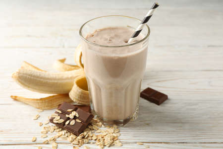 Glass of banana - chocolate milkshake on white wooden tableの写真素材