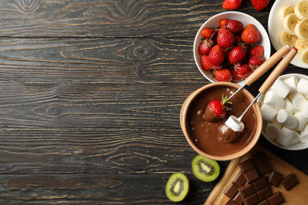 Composition with ingredients for chocolate fondue on wooden background. Cooking fondueの写真素材
