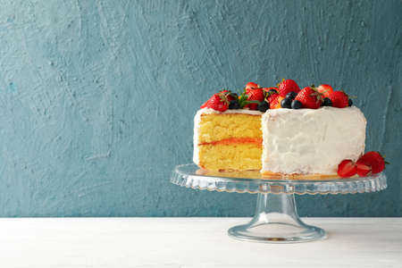 Tray with delicious berry cream cake on white wooden table. Tasty dessert