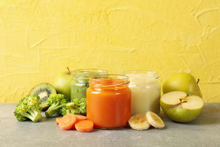 Composition with baby food on gray table against yellow backgroundの写真素材