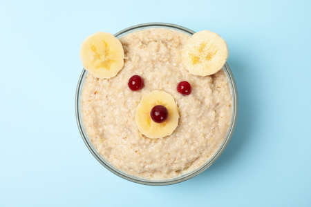 Bear face made of porridge and fruits on blue background, top view. Baby foodの写真素材