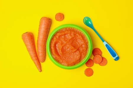 Bowl with vegetable puree on yellow background. Baby foodの写真素材