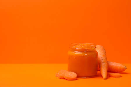 Composition with vegetable puree on orange background. Baby foodの写真素材