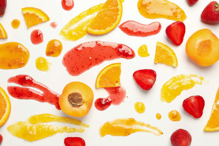 Apricot, strawberry, orange and jams on white background